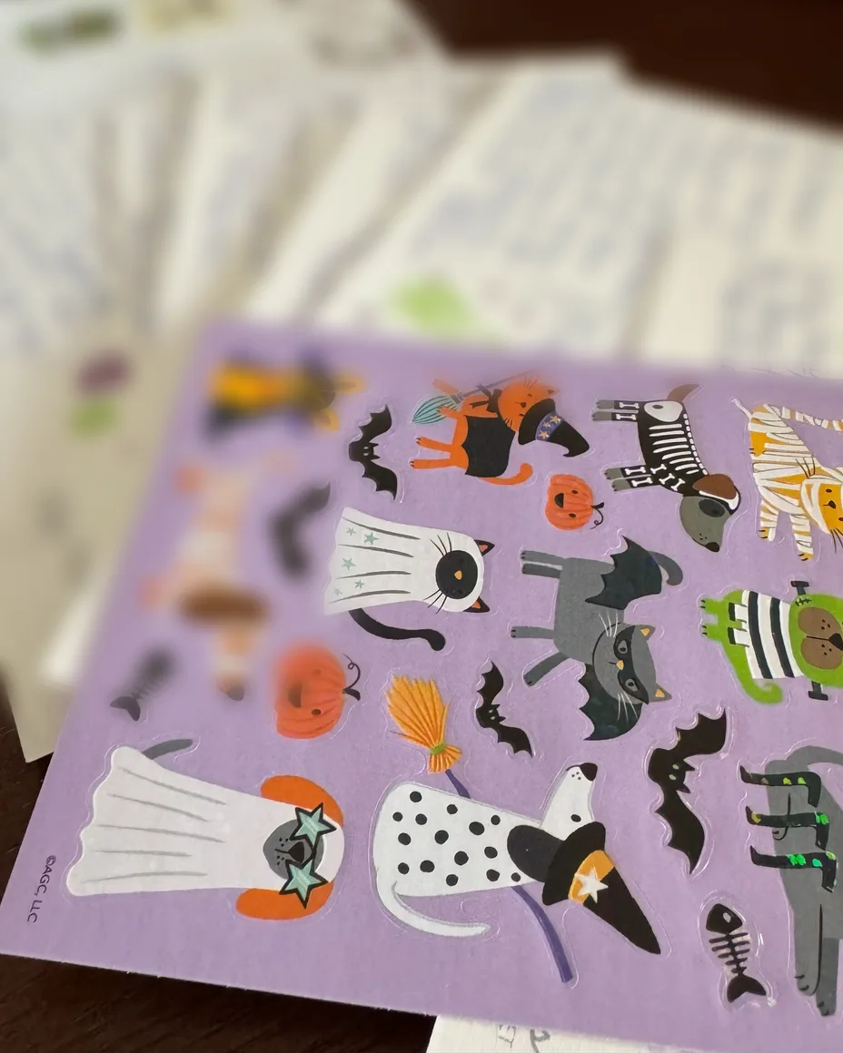 Halloween cat stickers on a stack of handwritten letters, a bunny mug behind.