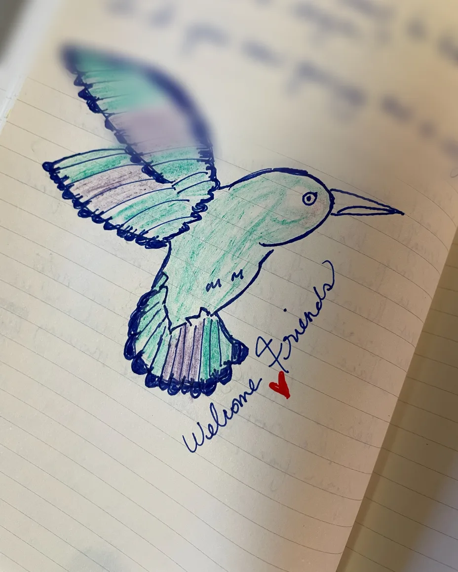 Her drawing of a hummingbird in blue ink and colored pencil, 'Welcome friends' written beside it.