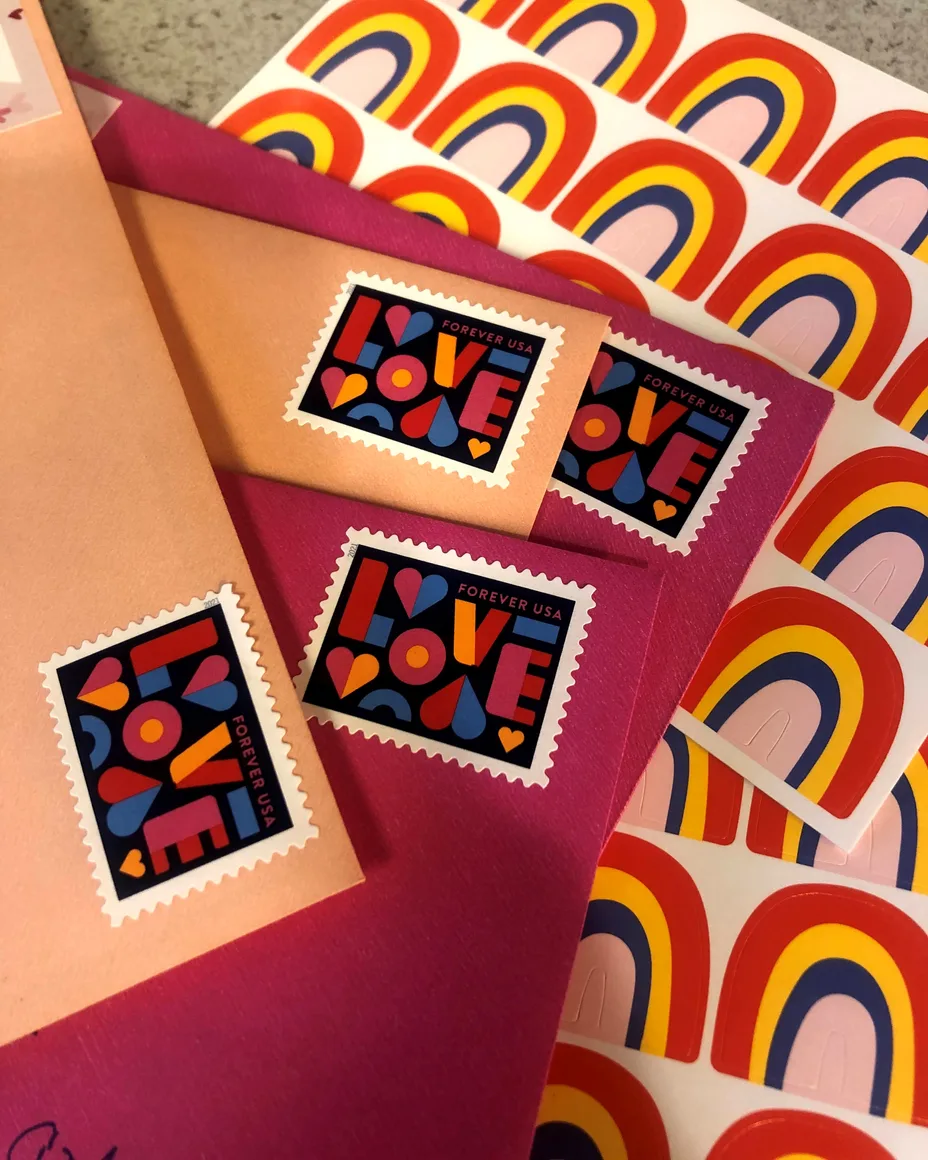 LOVE stamps on bright envelopes, with rainbow stickers.