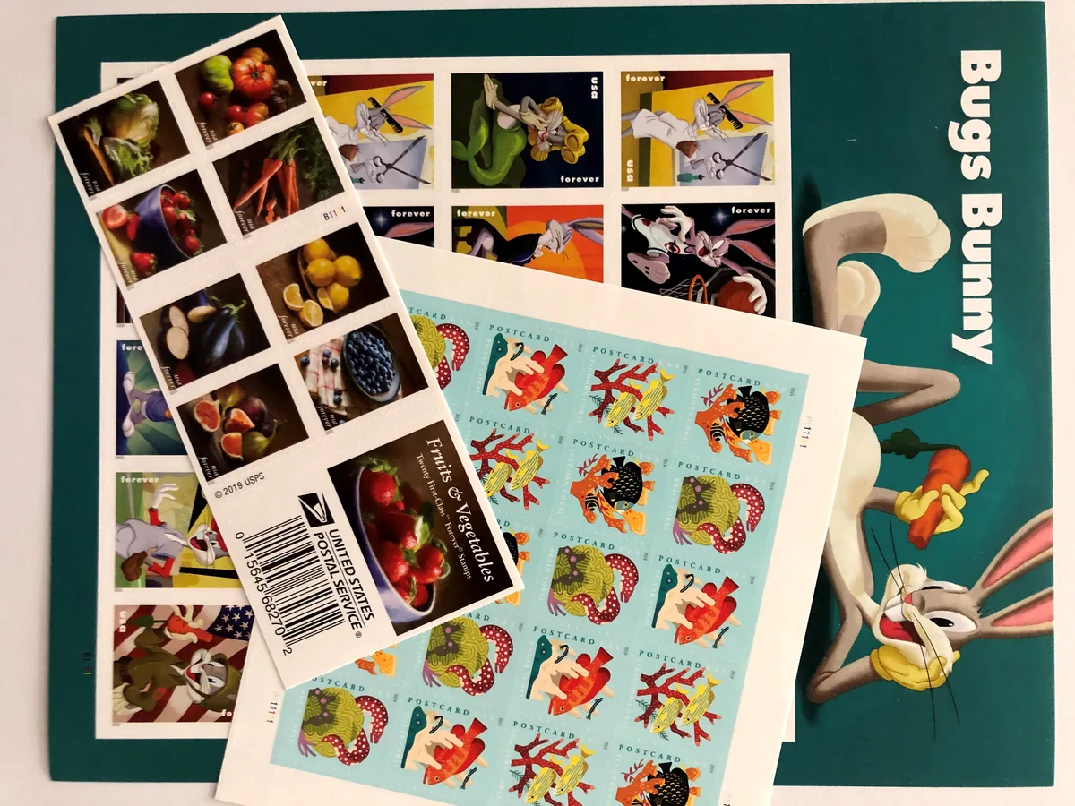 Sheets of stamps: fruits and vegetables, Bugs Bunny, and postcard stamps.